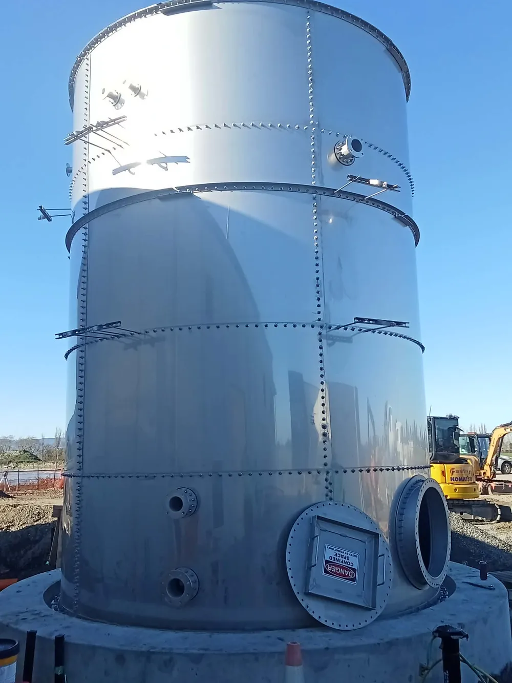 Tall galvanised bolted steel tank on a build site
