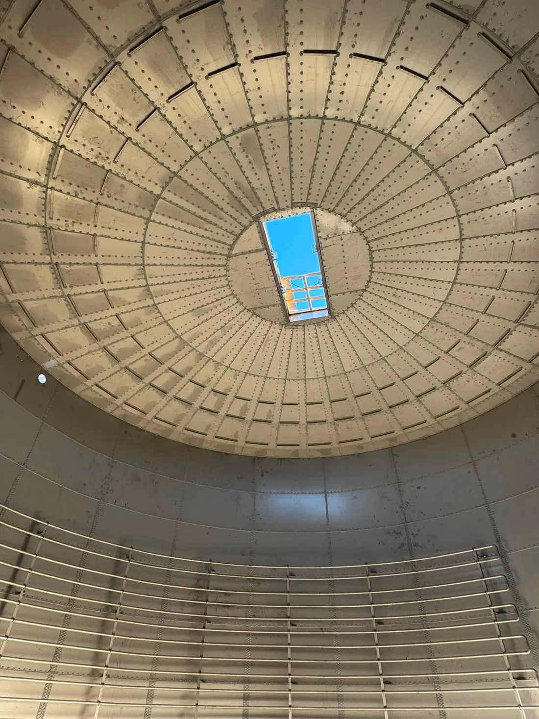 Looking straight up inside a completed tank at its domed roof, open sky visible through the single roof hatch