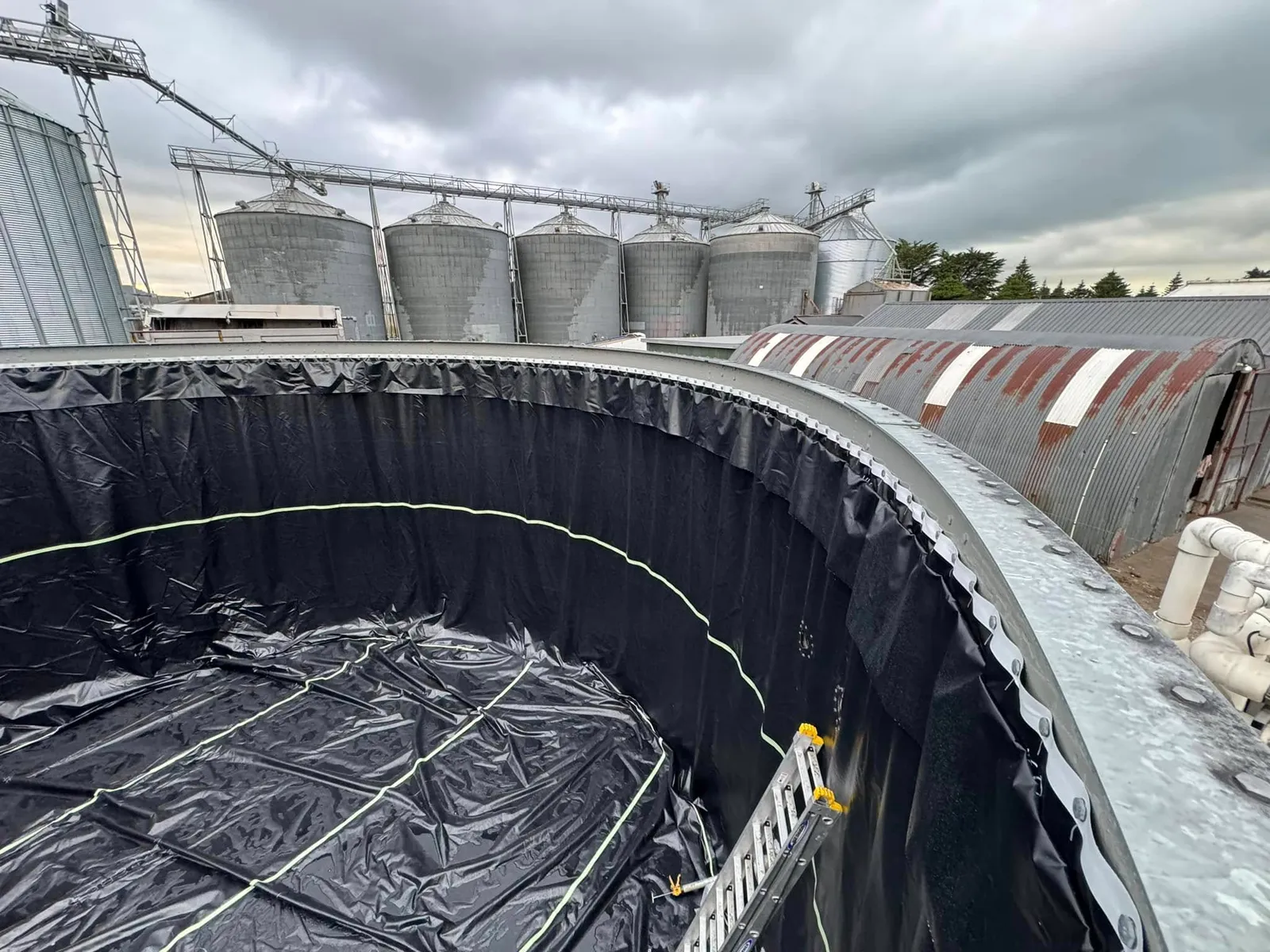 The new black liner hung around the inside wall of a tank shell and laid across the floor, seen from the top of the wall